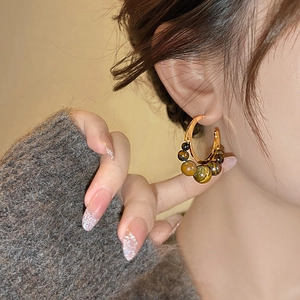Close-up of vintage C-shaped gold hoop earrings featuring natural tiger eye stone beads
