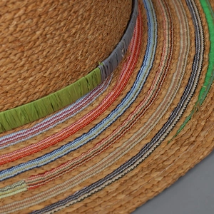 Macro detail of natural straw hat with colorful striped edges and woven textures