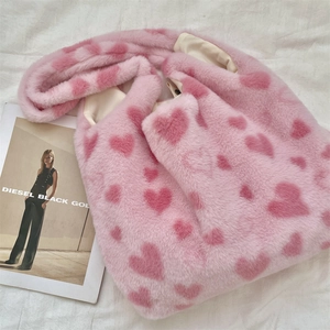 Detail view of pink fluffy plush fabric with red heart patterns and soft texture