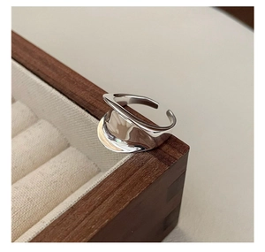 Detailed macro view of an S925 sterling silver liquid metal style saddle ring on wood