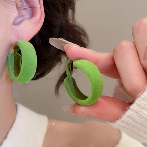 Gros plan sur les créoles vertes en forme de C avec texture floquée et fini velouté doux