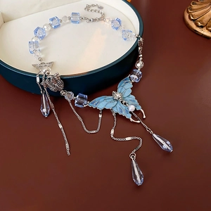 Détail du collier papillon bleu en cristal avec pompons argentés dans son écrin