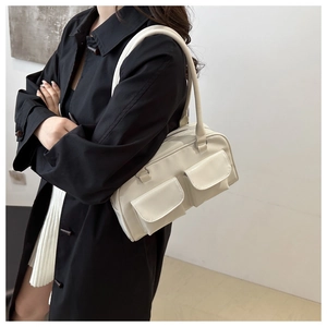 Dettaglio di una borsa a tracolla bianca quadrata con doppie tasche indossata da una modella