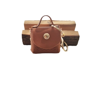Mini brown PU leather bag keychain with wave texture and gold hardware on wood blocks