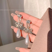 Close-up of elegant bow-shaped earrings with rhinestones and waterdrop pearls