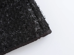 Detailansicht von hochwertigem schwarzem Tweed-Stoff mit schimmernden Fäden und Naht