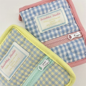 Close-up of quilted cotton storage pouches with colorful plaid patterns and zip closure