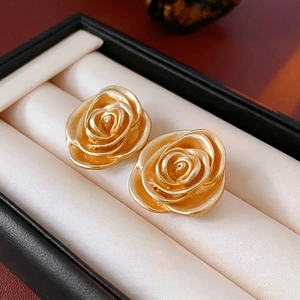Vintage gold rose flower earrings with layered petals on black textured jewelry box
