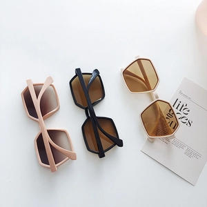 Flat lay of three large square frame sunglasses in pink, black, and beige colors