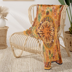 Ethnic sun mandala flannel blanket draped on a wicker rocking chair in natural light