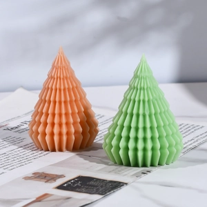 Detailed view of textured Christmas tree candles in green and orange on a stone table