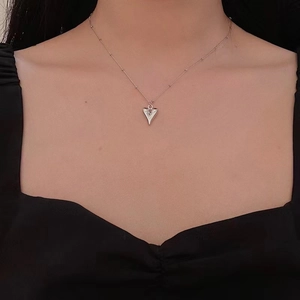 Close-up of a silver 3D heart pendant on a delicate beaded chain worn by a model
