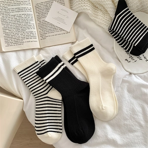 Flat lay of black and white striped wool blend socks on soft bedding with cozy decor