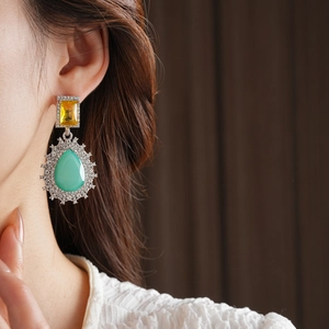 Détail de boucles d'oreilles vintage style palais avec cristaux jaunes et menthe