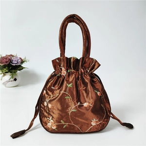 Detailed view of brown satin drawstring bag featuring intricate floral embroidery