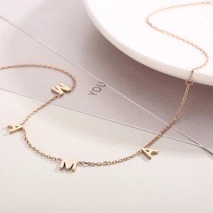 Detail of rose gold MAMA letter necklace on minimalist elegant jewelry display