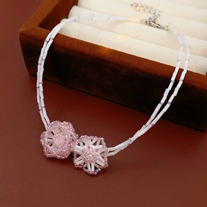 Close-up of double-layer beaded necklace featuring delicate pink and white floral charms