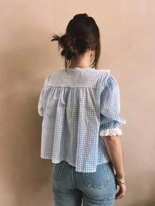 Detail of blue plaid bubble sleeves with white lace trim and back pleats on a blouse