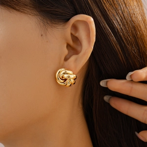 Detailed view of the gold twisted knot earring worn by a model in a minimal setting