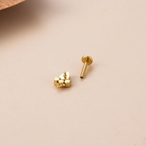 Macro view of gold G23 titanium labret stud showing internal threading and cubic zirconia
