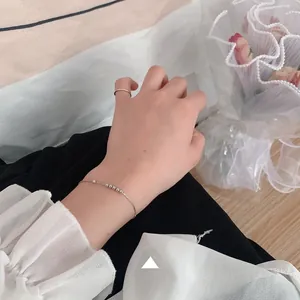 Detail of minimalist 925 silver beaded bracelet and thin ring on woman wrist