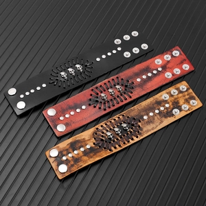 Detailed view of three punk leather wristbands with skull metal studs and braided design