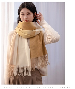 Detailed view of beige and khaki plaid scarf with fringe tassels on a soft cashmere texture