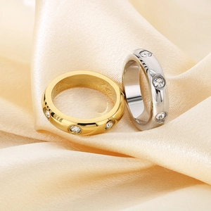 Detailed view of gold and silver polished rings with inlaid crystals on satin fabric