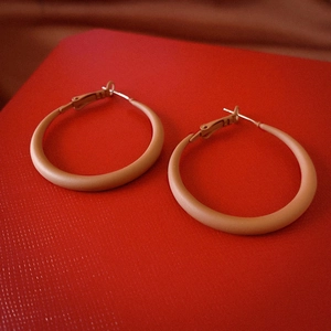 Macro view of vintage geometric matte orange resin hoop earrings with silver needles