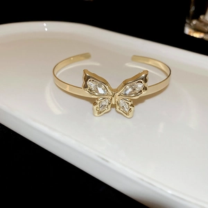 Detail view of a gold butterfly open cuff bracelet with sparkling marquise-cut rhinestones