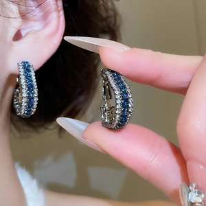 Detailed view of C-shaped earrings with navy blue square and white round cubic zirconia