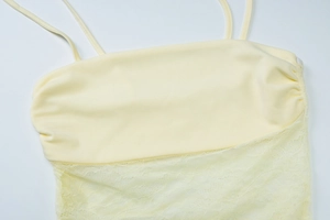 Detail of pale yellow lace patchwork camisole with delicate straps and hollow embroidery