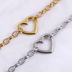Detail of gold and silver chunky chain necklaces with heart-shaped clasps on white fabric
