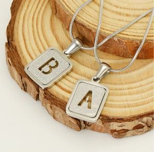 Détail macro de pendentifs lettres A et B avec texture sablée sur support en bois