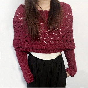 Detail view of dark red knit shawl featuring intricate hollow weave and ribbed sleeve cuffs