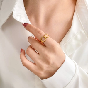 Close-up of golden interlocking oval rings on finger with polished mirror finish