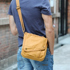 Minimalist yellow canvas crossbody bag with adjustable strap worn by male model outdoors