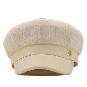 Macro detail of beige knit newsboy hat with a synthetic leather brim and metal M logo