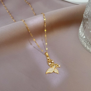 Close-up of golden butterfly pendant with clear zircon inlay on pink silk fabric