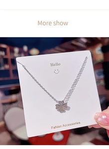 Detail of silver clover pendant necklace with inlaid white diamonds and mirror finish
