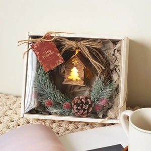 Christmas wreath gift box with red berries, pine cones and luminous wooden house decor