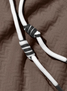 Close-up of brown wavy jacquard fabric texture and white drawstring with striped detail