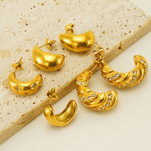 Close-up of three pairs of gold stainless steel hoop earrings with crystal accents on stone