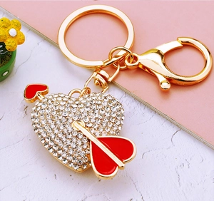 Close-up of heart and arrow gold keychain with sparkling rhinestones and red enamel