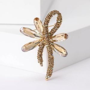 Macro detail of golden dragonfly brooch with sparkling crystals and champagne rhinestones