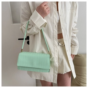 Close-up of mint green underarm bag with minimalist woven texture and gold hardware