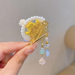 Detail of flower hair clip with pearls, gold hollow metalwork, and tassel pendants