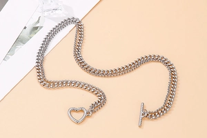 Detail of silver double-layer chain necklace featuring a textured heart-shaped OT buckle