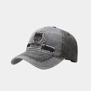 Close-up of vintage washed grey denim baseball cap with wolf head embroidery and patches