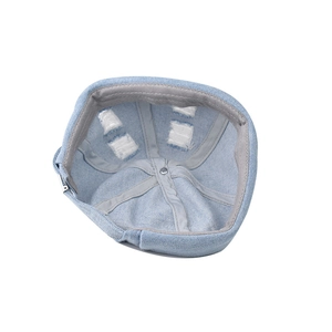 Detail view showing gray webbing lining and metal top button of the worn denim docker hat